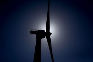 GROUND VIEW OF A SILHOUETTE OF A WIND MILL IN FRONT OF THE SUN.