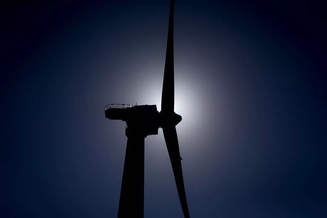 GROUND VIEW OF A SILHOUETTE OF A WIND MILL IN FRONT OF THE SUN.