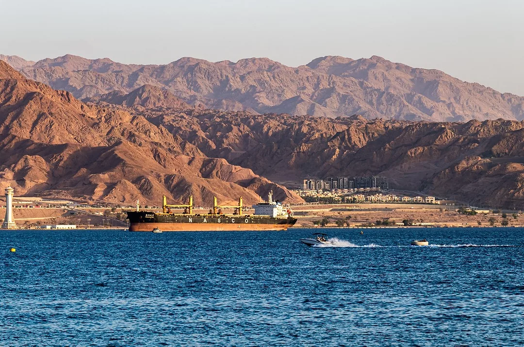 A SHIP AT SEA IS FRAMED BY MOUNTAINOUS DESERT