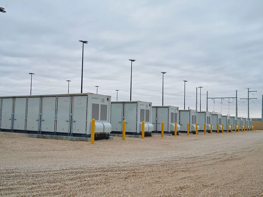 SEVERAL LARG LITHIUM-ION STORAGE BATTERIES UNDER A GRAY SKY.