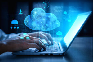 A DIGITAL RENDERING OF A CLOUD AND LOGOS AROUND THE CLOUD HOVER ABOVE A PERSON'S HANDS ON A LAPTOP.