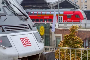 TWO TRAINS SIT IN A STATION, THE ONE IN THE FOREGROUND BEARING THE LETTERS DB.