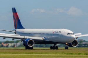 A PLANE WITH THE DELTA INSIGNIA SITS ON A RUNWAY