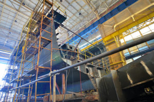 A LARGE CARGO SHIP BEING BUILT INSIDE OF A SHIPYARD.