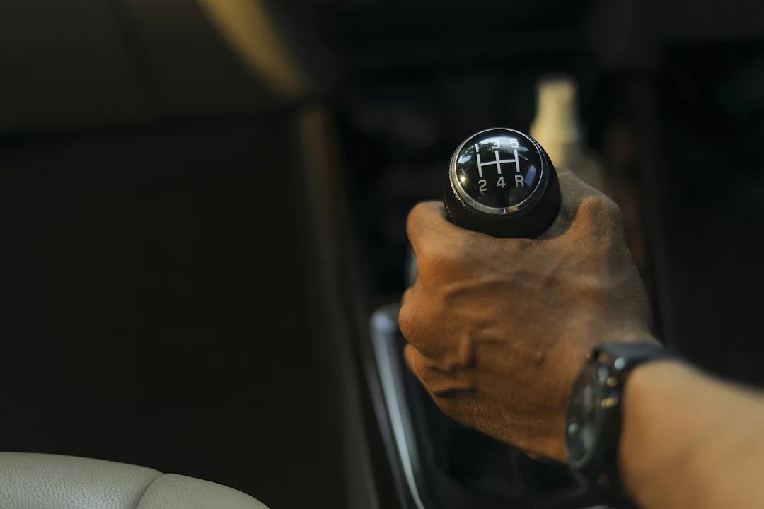 A PERSON'S HAND CAN BE SEEN ON THE GEAR STICK OF AN AUDI.