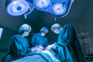 A TEAM OF THREE DOCTORS PERFORMING HEART SURGERY IN AN EMERGENCY SURGICAL ROOM.
