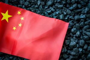 A CHINESE FLAG LAYS ON TOP OF A PILE OF COAL.