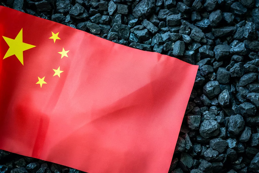 A CHINESE FLAG LAYS ON TOP OF A PILE OF COAL.
