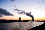 SILHOUETTE OF A NUCLEAR POWER PLANT WITH SMOKE BILLOWING OUT OF THE TOP OF ONE OF THE REACTORS.