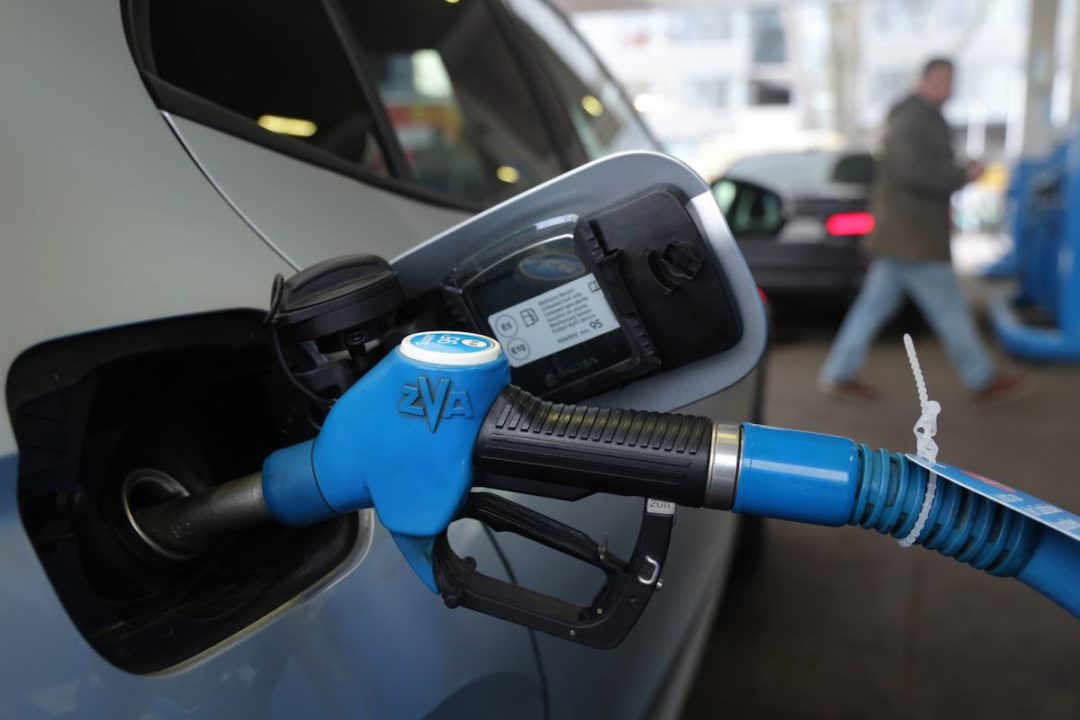 A BLUE GAS NOZZLE IN THE FUEL TANK OF A CAR.