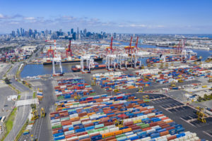 AERIAL VIEW OF THE PORT OF MELBOURNE UNDER A BLUE SKY WITH THE MELBOURNE SKYLINE IN THE BACKGROUND.