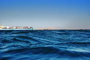A cargo ship on the horizon of the ocean