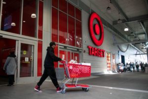A shopper in a baseball cap leaves a Target store pushing a shopping cart