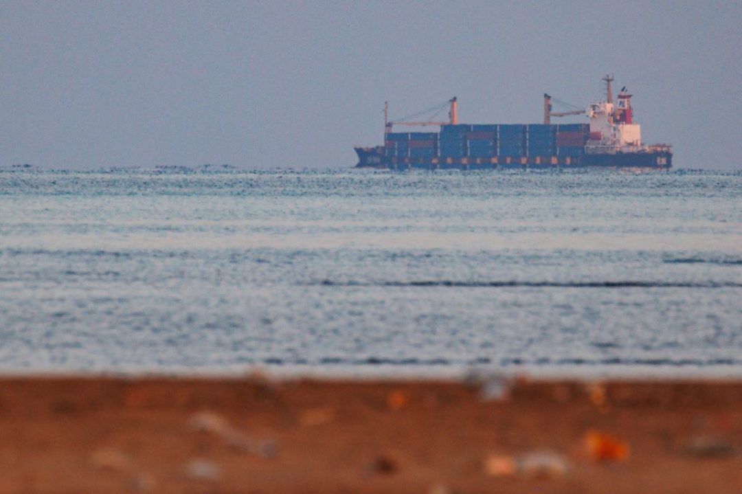 A CONTAINER SHIP AT SEA IS SEEN FROM THE SHORE