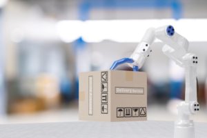 A WHITE ROBOTIC ARM GRABS A CARDBOARD BOX