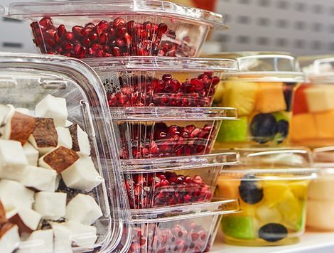 STACKS OF CLEAR PLASTIC CLAMSHELL PACKAGING HOLD CHOPPED COCONUT, POMEGRANATE SEEDS AND MELON.