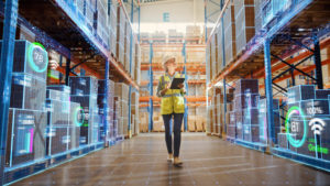 A woman with a tablet walking in between two shelves in a warehouse