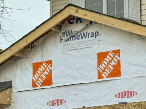 An unfinished house under construction with Home Depot logos on its wrapping