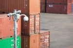 Shipping containers in a port with security cameras in the foreground.
