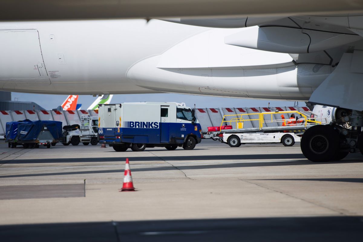 A brinks security van beside a boeing co 777 passenger plane. photographer nathan laine bloomberg 