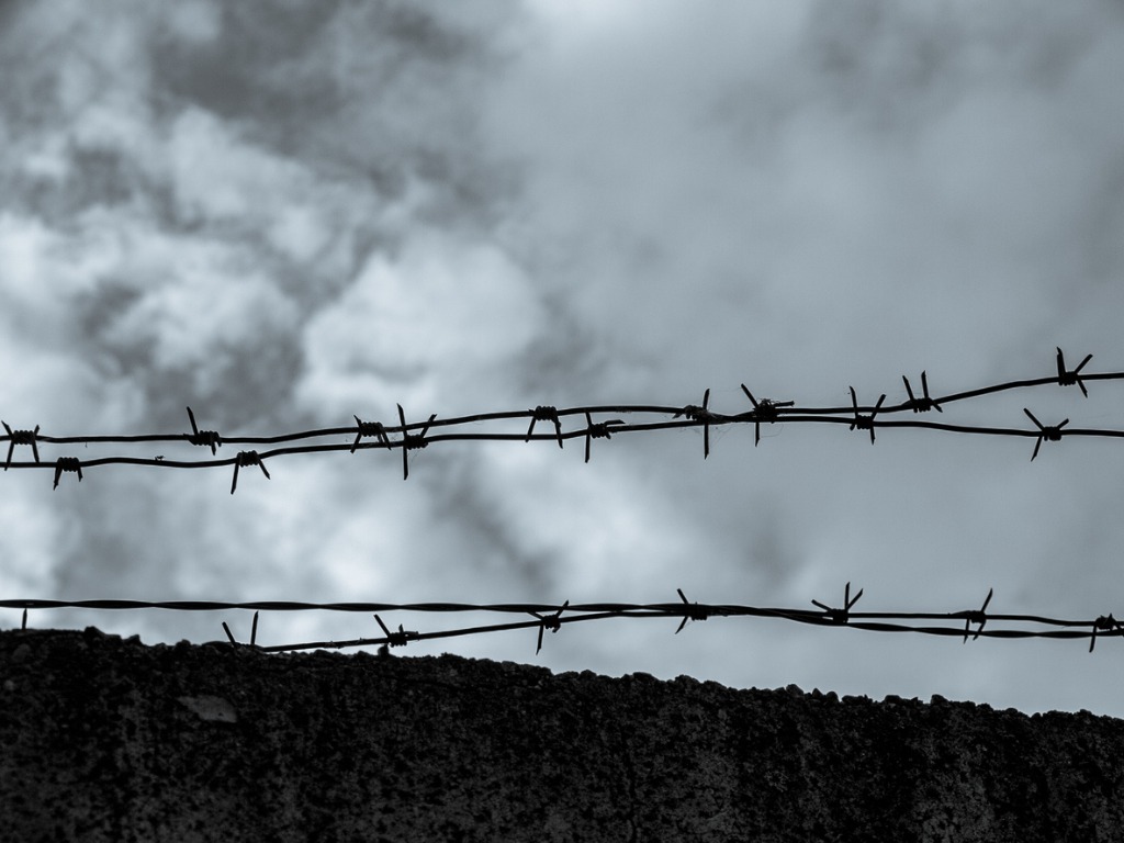 Barbed wire over a concrete fence close up closed territory military facility.jpg s1024x1024wisk20cvvscjf joev8rpiu4yrshr38raginvy0xxt8uvx11qa