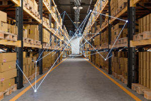 Boxes stacked in a warehouse connected by a bright blue line