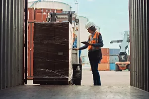 A woman checking a cargo shipment on a port dock