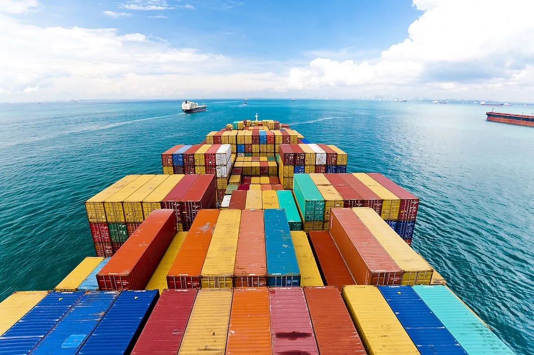 Horizontal wide angle view of heavy loaded container cargo ship in busy strait of Malacca