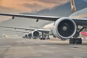 A row of airplanes on a runway, displaying the right wing and engine of each one