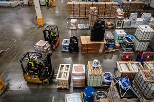 A BIRD'S EYE VIEW OF A BUSY WAREHOUSE, WITH GOODS ON PALLETS AND FORKLIFT TRUCKS