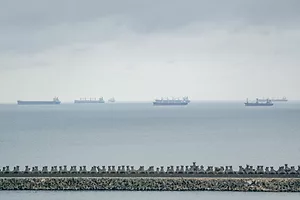 A LINE OF TANKER SHIPS FAR OFF ON THE SEA'S HORIZON