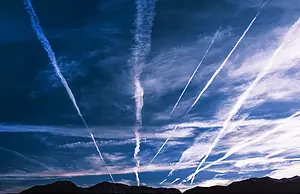 MULTIPLE WHITE VAPOR TRAILS STREAK ACROSS A BLUE SKY