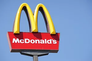 A large yellow 'M' on a signpost, above "McDonald's" written in white lettering on a red background.