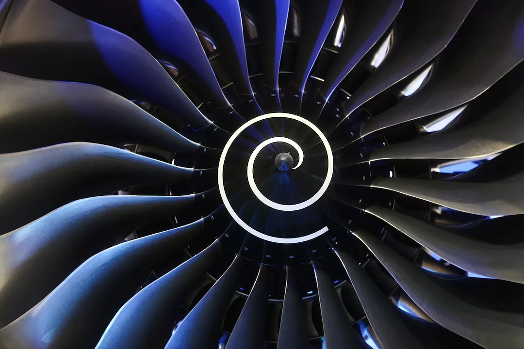 A close up of a turbine engine, with a white spiral pattern in the middle