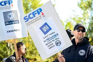 STRIKING WORKERS IN SUNGLASSES HOLD UP SIGNS IN FRENCH
