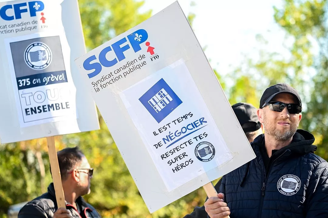 STRIKING WORKERS IN SUNGLASSES HOLD UP SIGNS IN FRENCH