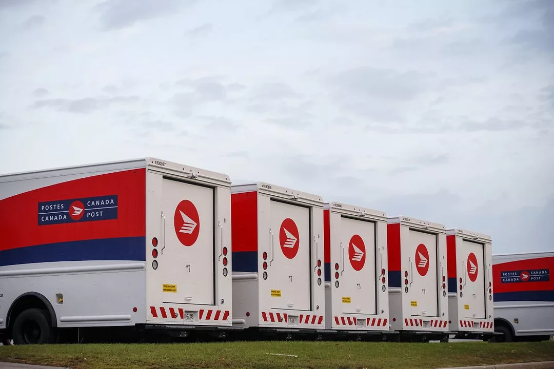 FIVE BOX TRUCKS PARKED IN A ROW BEAR THE CANADA POST INSIGNIA