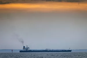 AN OIL TANKER PLIES THE SEAS UNDER A GREY AND APRICOT SKY