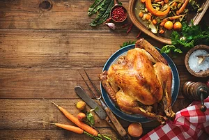 An overhead view of a cooked turkey on blue serving plate sitting on a wood table.