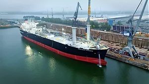 A LARGE TANKER SHIP SPORTS TWO UNUSUAL, UPRIGHT, CYLINDRICAL STRUCTURES TOWARD THE BOW END OF ITS DECK