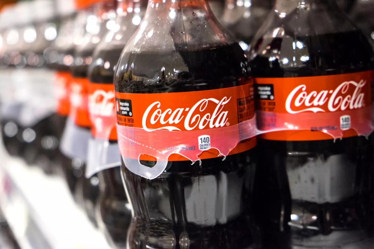 Bir rafta Coca-Cola etiketli düzinelerce plastik şişe sıralanmış