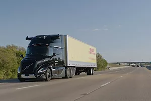 A semi-truck with a black cab pulling a yellow trailer bearing "DHL" in red lettering across the side