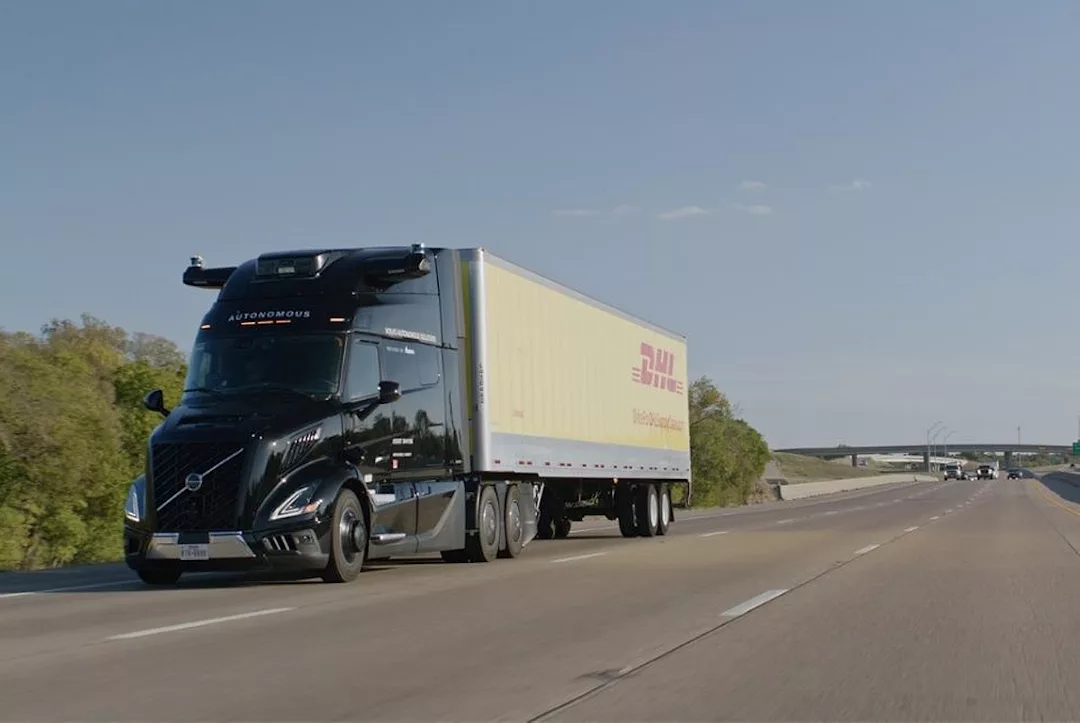 A semi-truck with a black cab pulling a yellow trailer bearing "DHL" in red lettering across the side