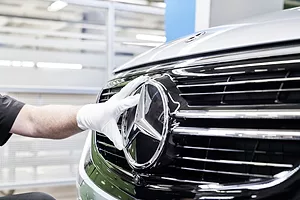 A GLOVED HAND PLACES A PLASTIC STAR INSIGNIA ON THE GRILLE OF A CAR