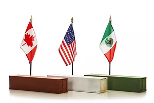A Canadian, American, and Mexican Flag lined up in a row, on top of a red, white and green shipping container respectively