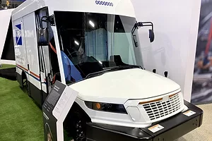 A SHINY WHITE POSTAL DELIVERY TRUCK BEARS THE BLUE USPS LOGO