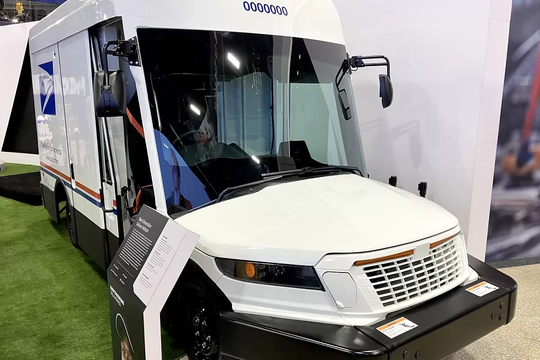 A SHINY WHITE POSTAL DELIVERY TRUCK BEARS THE BLUE USPS LOGO