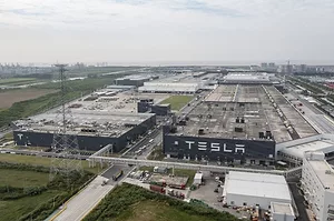 AN AERIAL SHOT OF A GIANT MANUFACTURING COMPOUND BEARS A LARGE SIGN SAYING TESLA