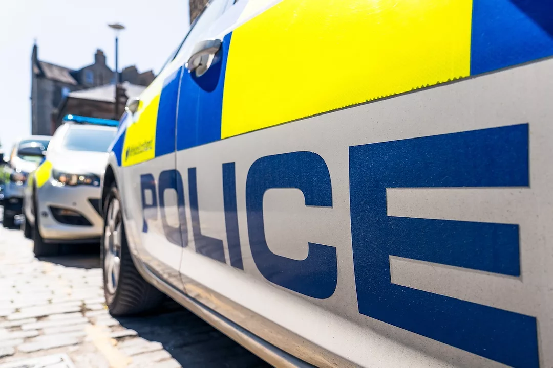 A blue, yellow and white car that reads "POLICE" in blue lettering across the side