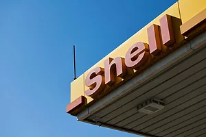  A SHELL GAS STATION LOGO ON THE CORNER OF A CANOPY IS FRAMED BY AN ELECTRIC BLUE SKY